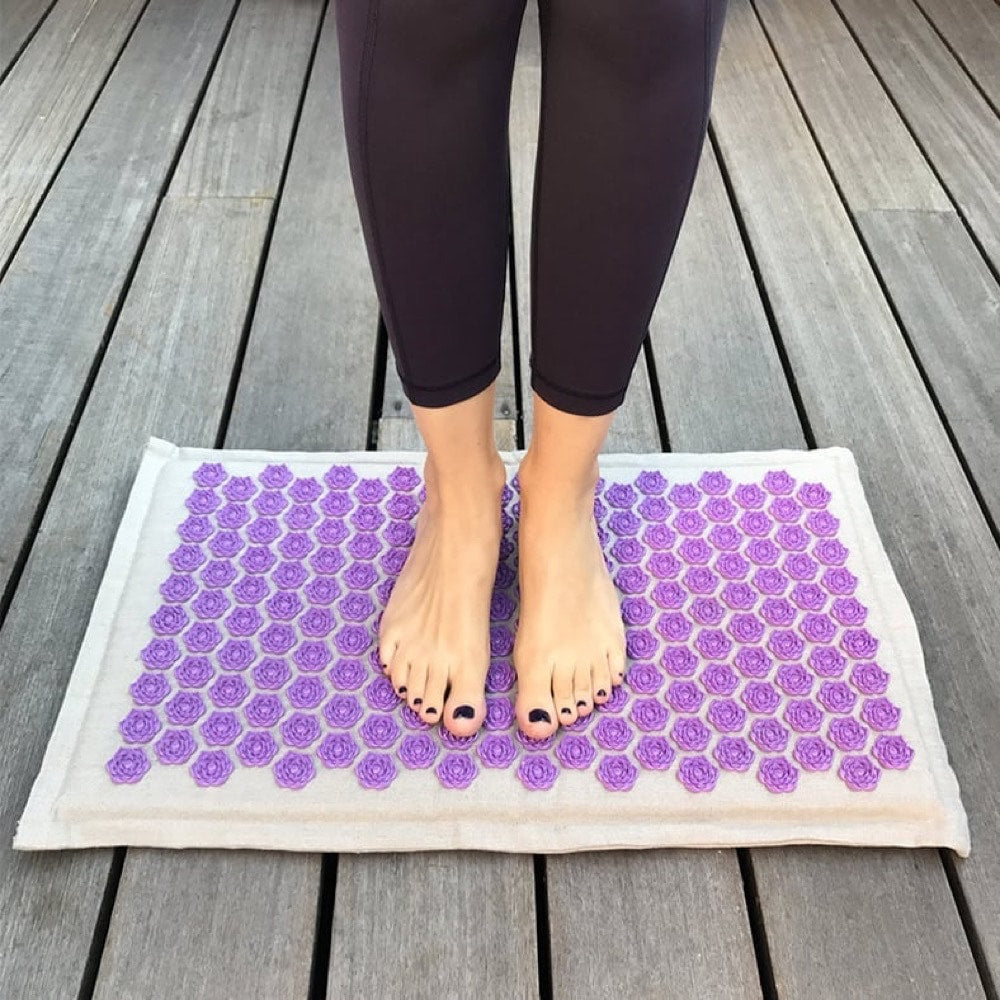 Les pieds d'une femme posés sur le tapis d'acupression éco-naturel Les Fleurs du Lotus™